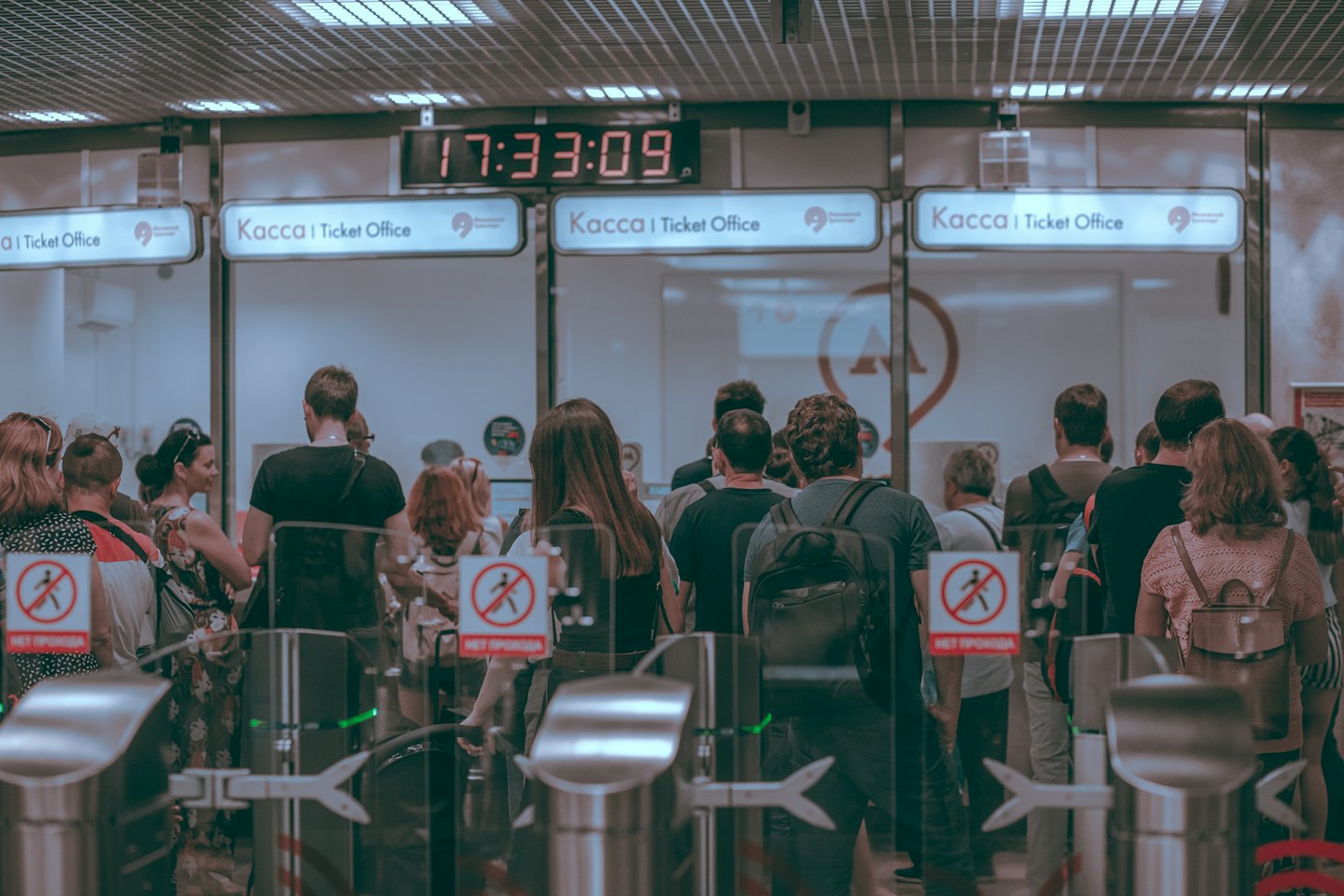 Commuters wait in line to pass through indoor turnstiles.